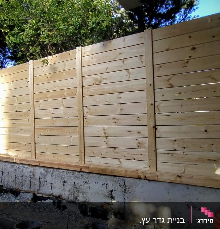 גדר עץ חדשה מותקנת בגינה עם קרקע חשופה